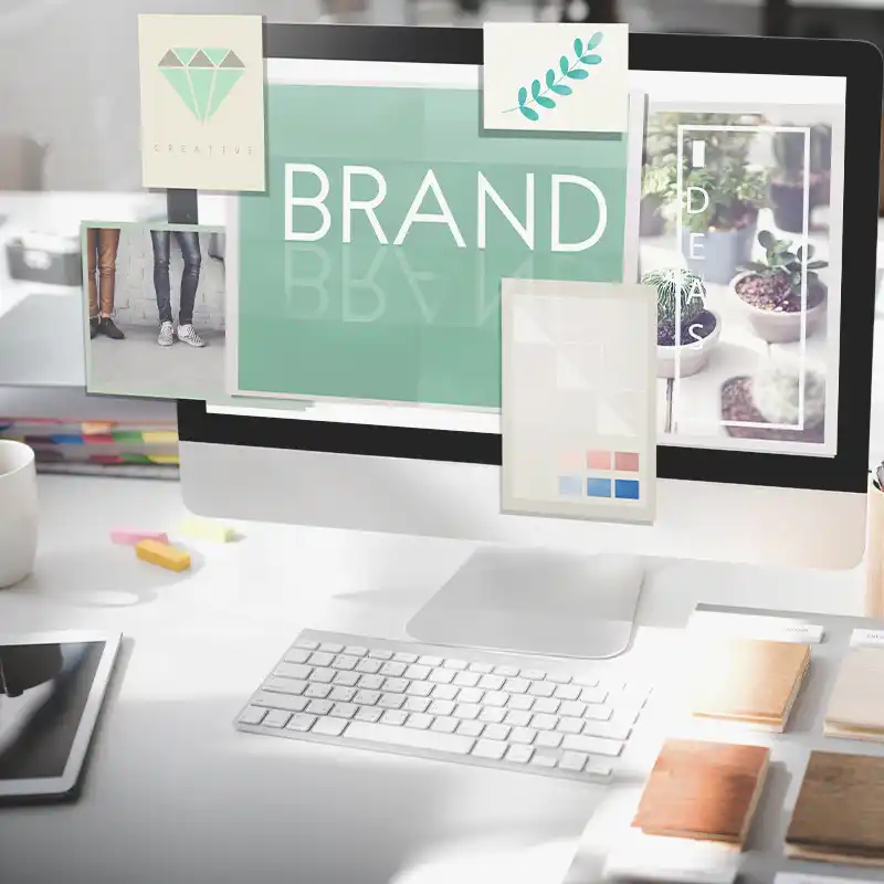 Modern workspace with computer displaying 'BRAND', surrounded by visuals representing creativity and messaging strategy development.