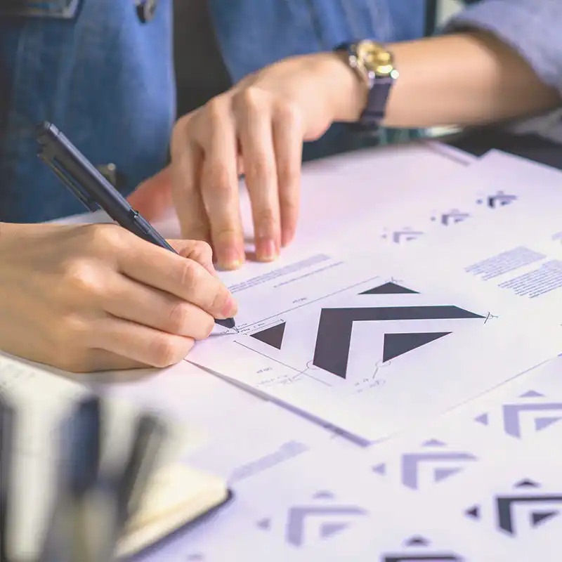 Person sketching geometric logo design, symbolizing Artmedia Digital's expertise in creative branding, web design, and marketing solutions.