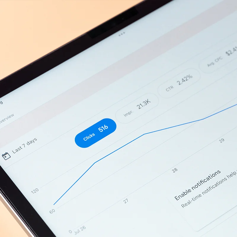 Tablet screen showing a line graph of clicks and impressions from web analytics, representing digital marketing analytics and reporting.