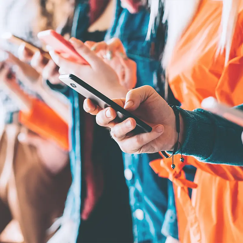 Close-up of people using smartphones in a public setting, concept for local SEO citations, mobile search, and hyperlocal marketing engagement.