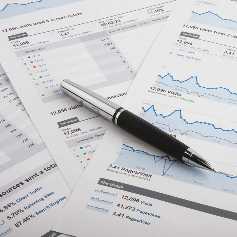 Pen on analytics reports displaying website visit data, indicative of managed PPC campaigns performance analysis.