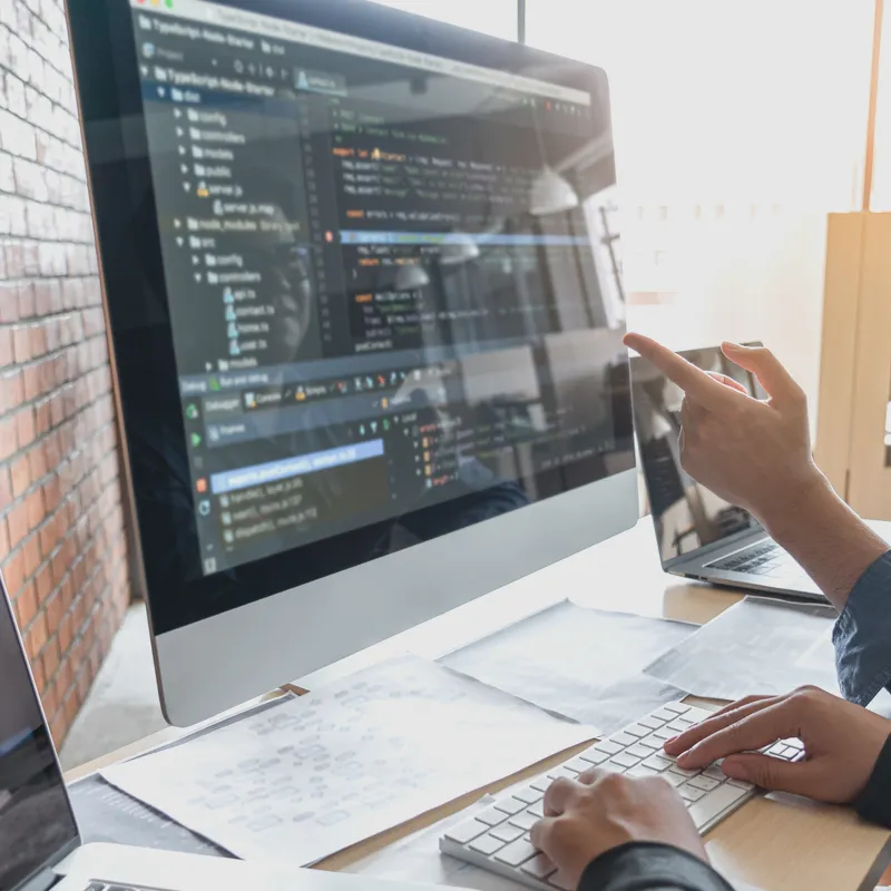 Close-up of a monitor showing website code and analytics, with hands performing an SEO Site Audit.