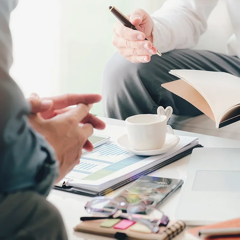 Two people engaged in a discussion over a report with graphs and a laptop, representing SEO strategy and optimization.