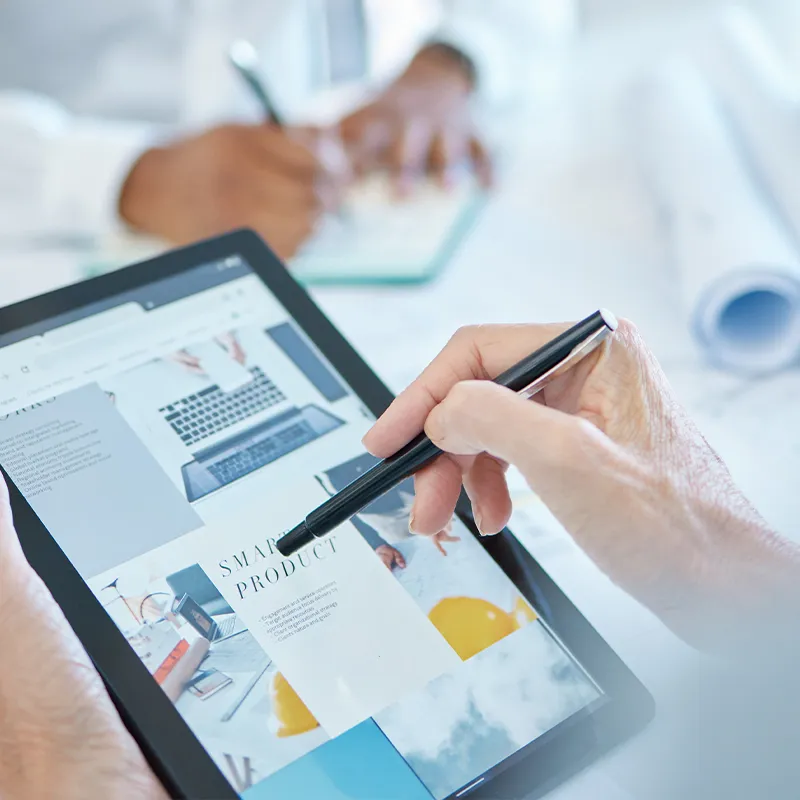 Hands holding a tablet displaying digital ads with a stylus, illustrating social media marketing and advertising.