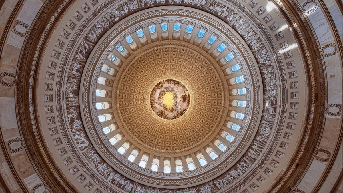 Interior of a historic civic building dome with detailed architecture and central mural, representing authority, governance, and trusted institutions.
